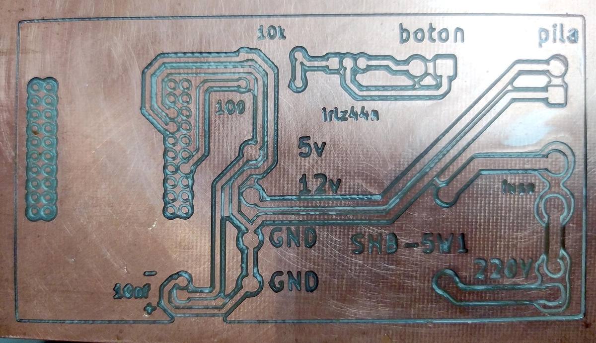 PCB recién fresada en la CNC: se ven las pistas de cobre aisladas y el texto grabado con etiquetas de cada punto de conexión