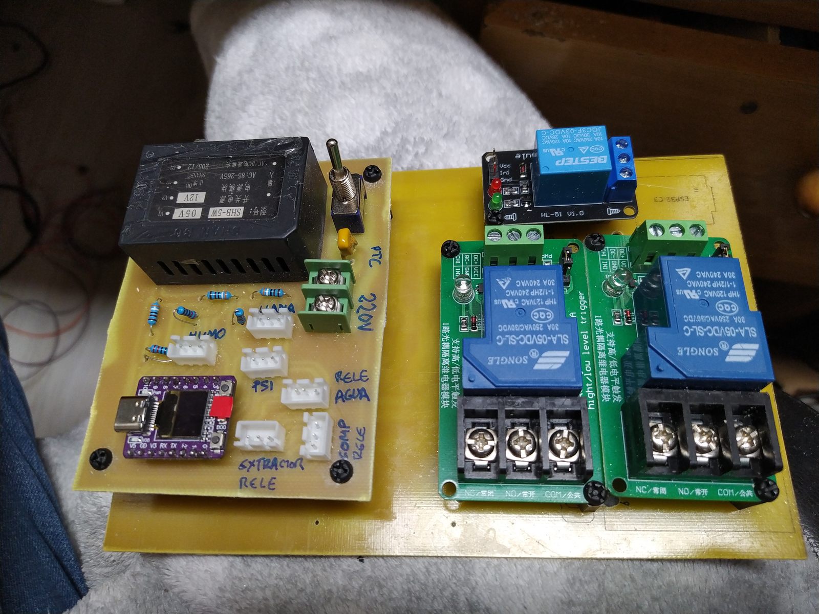PakuLaser ensamblado: placa de control con ESP32-C3 SuperMini y fuente SHB-5W1, junto a dos módulos de relés 30A Songle y un relé pequeño, montados en base de fenólico amarillo