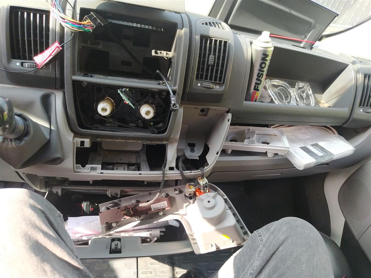 Salpicadero de la Citroën Jumper desmontado para acceder al módulo de climatización: consola central extraída, cableado a la vista y piezas apoyadas en el asiento del copiloto